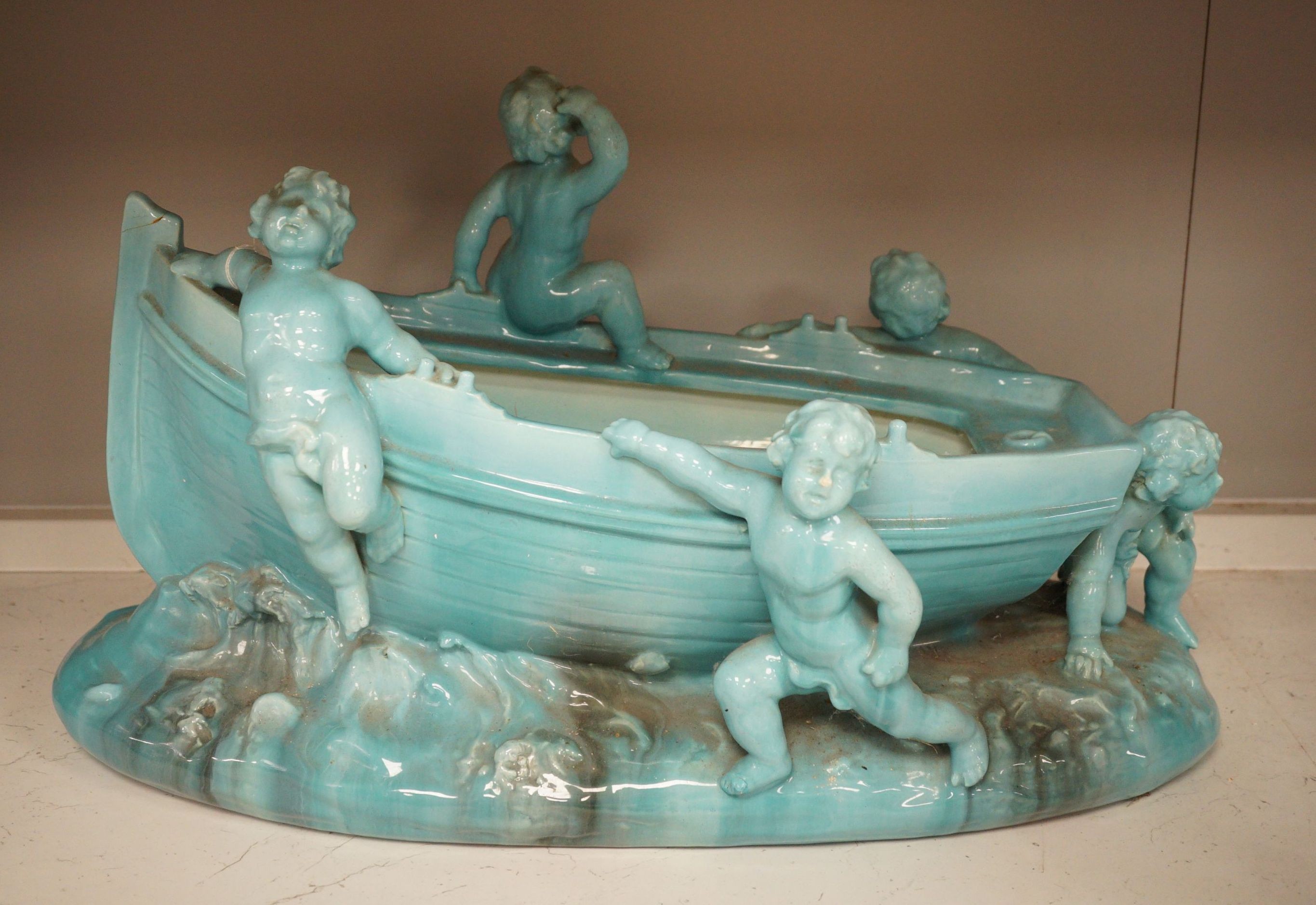 A large Continental majolica centrepiece with cherub figures and boat, 56cm